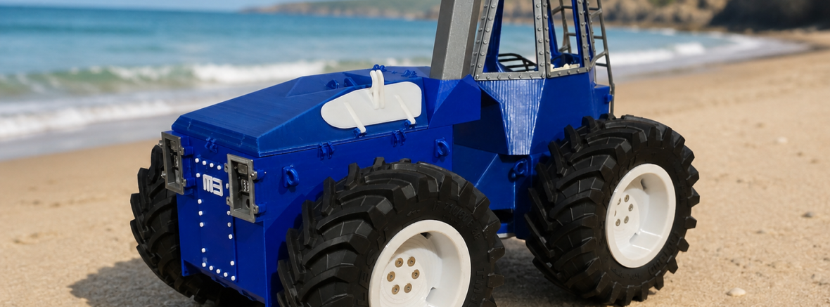 A photo of our prototype tractor kit facing from right to left, digitally altered to be shown on a sandy beach with blue seas and cliffs behind.