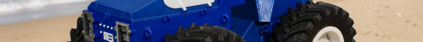 A photo of our prototype tractor kit facing from right to left, digitally altered to be shown on a sandy beach with blue seas and cliffs behind.