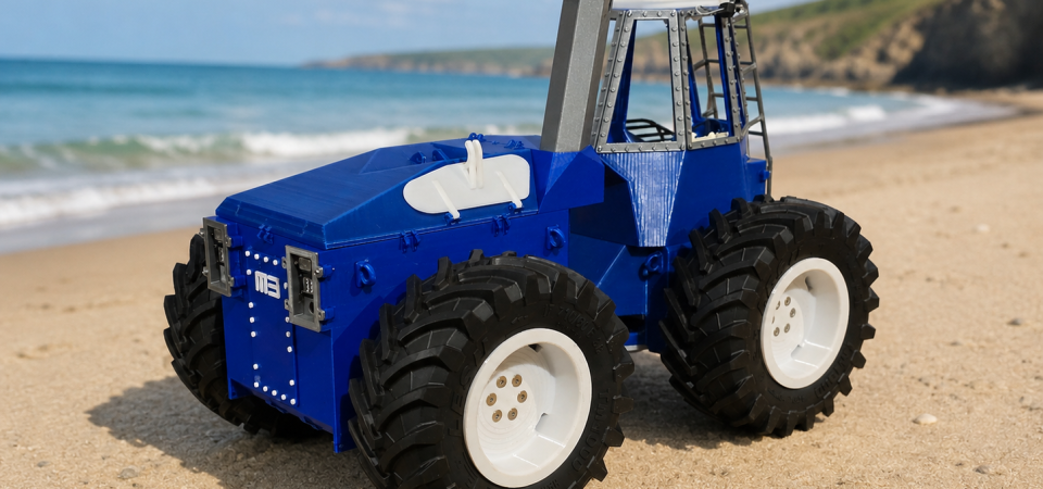 A photo of our prototype tractor kit facing from right to left, digitally altered to be shown on a sandy beach with blue seas and cliffs behind.